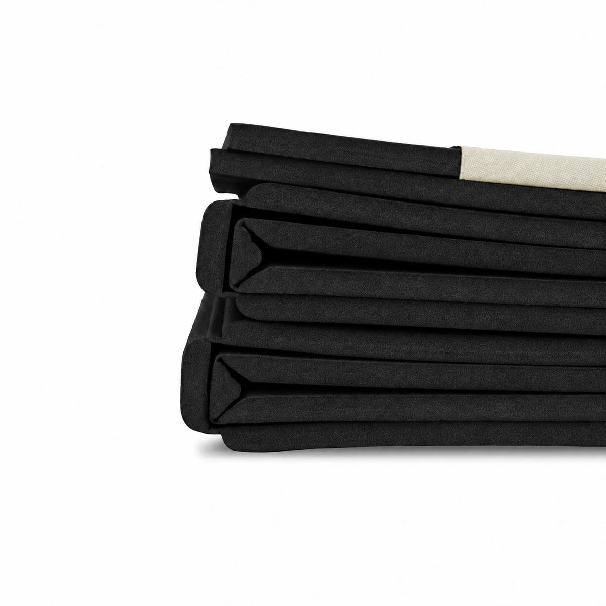 Side view of a black Movement Mat folded into a compact stack, showing its layered edges.